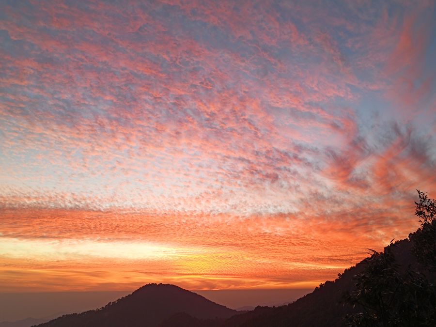 Amber sunset with painted cloud cover over the hills