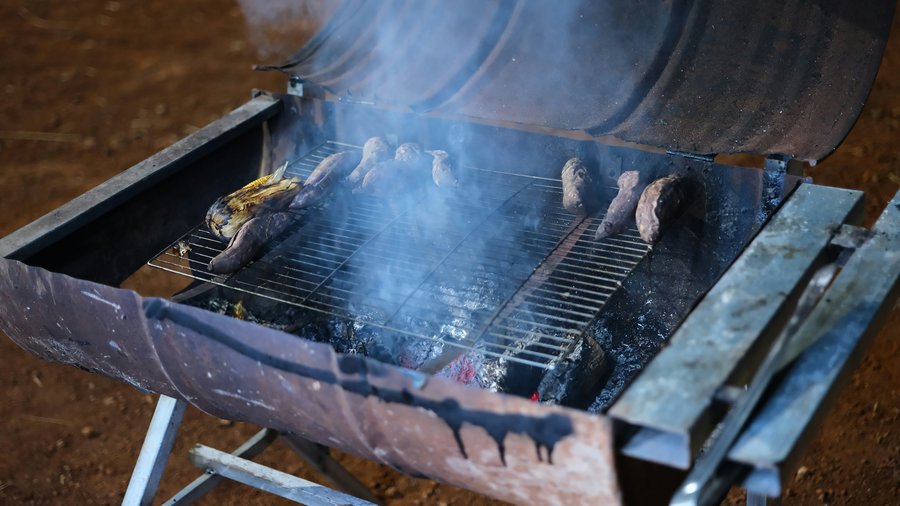 Mountain barbeque grill with smoke, sweetcorn and coals on the lawn