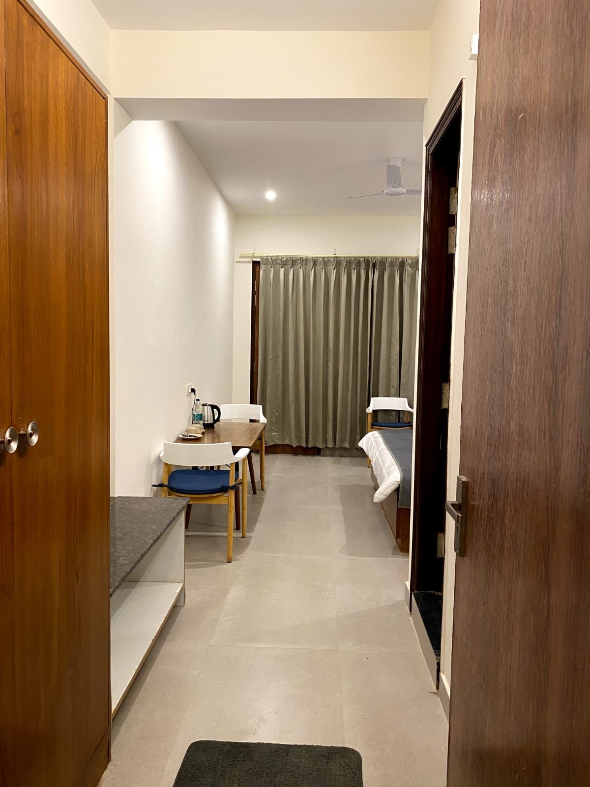 Another Deluxe room with a wood-slatted headboard wall, navy bedding and balcony doors letting in afternoon light