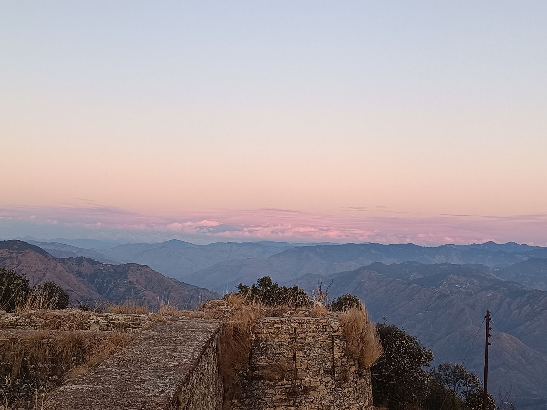 View from the abandoned fort: layered Himachal ranges at sunset