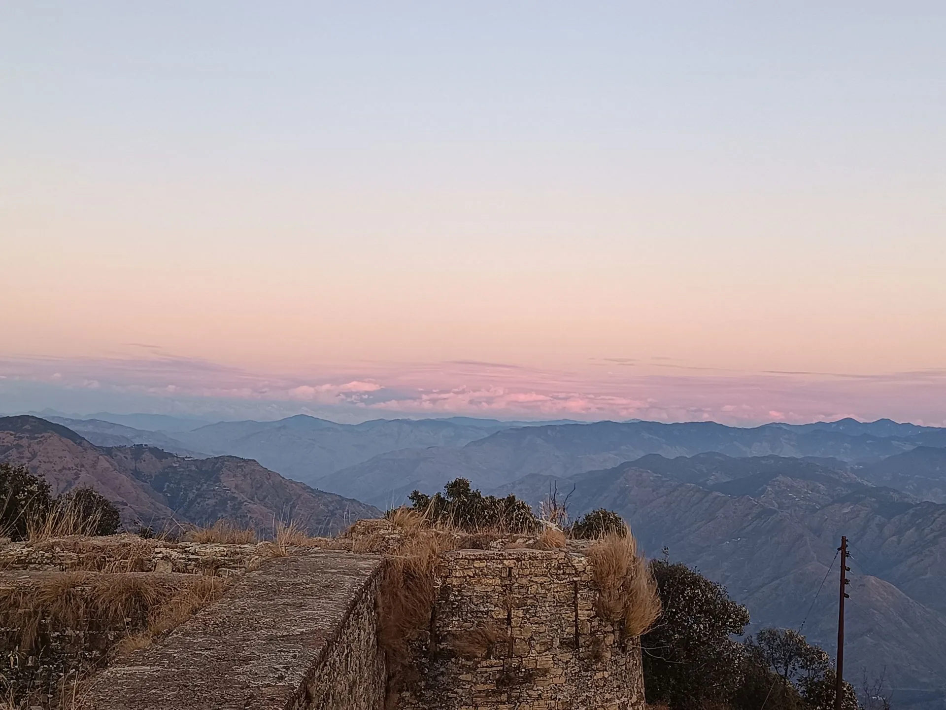View from the abandoned fort: layered Himachal ranges at sunset