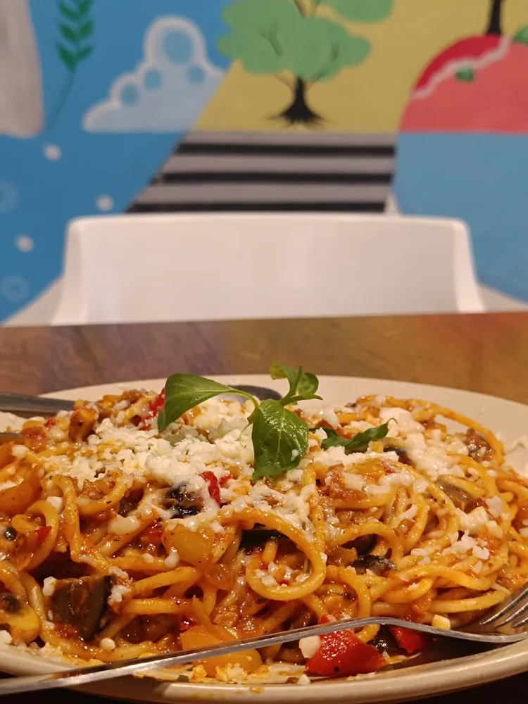 Plate of fresh spaghetti with mushrooms, peppers and grated cheese topped with basil, served at the Windmill Inn café in Solan