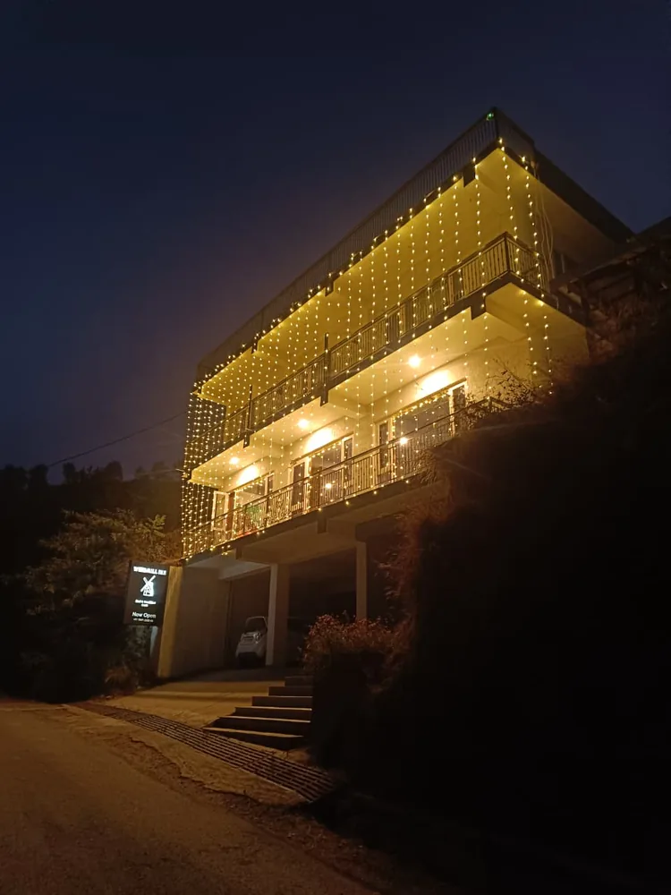 Windmill Inn lit up with Diwali fairy lights wrapping around three floors of balconies at night — a mountain homestay near Solan