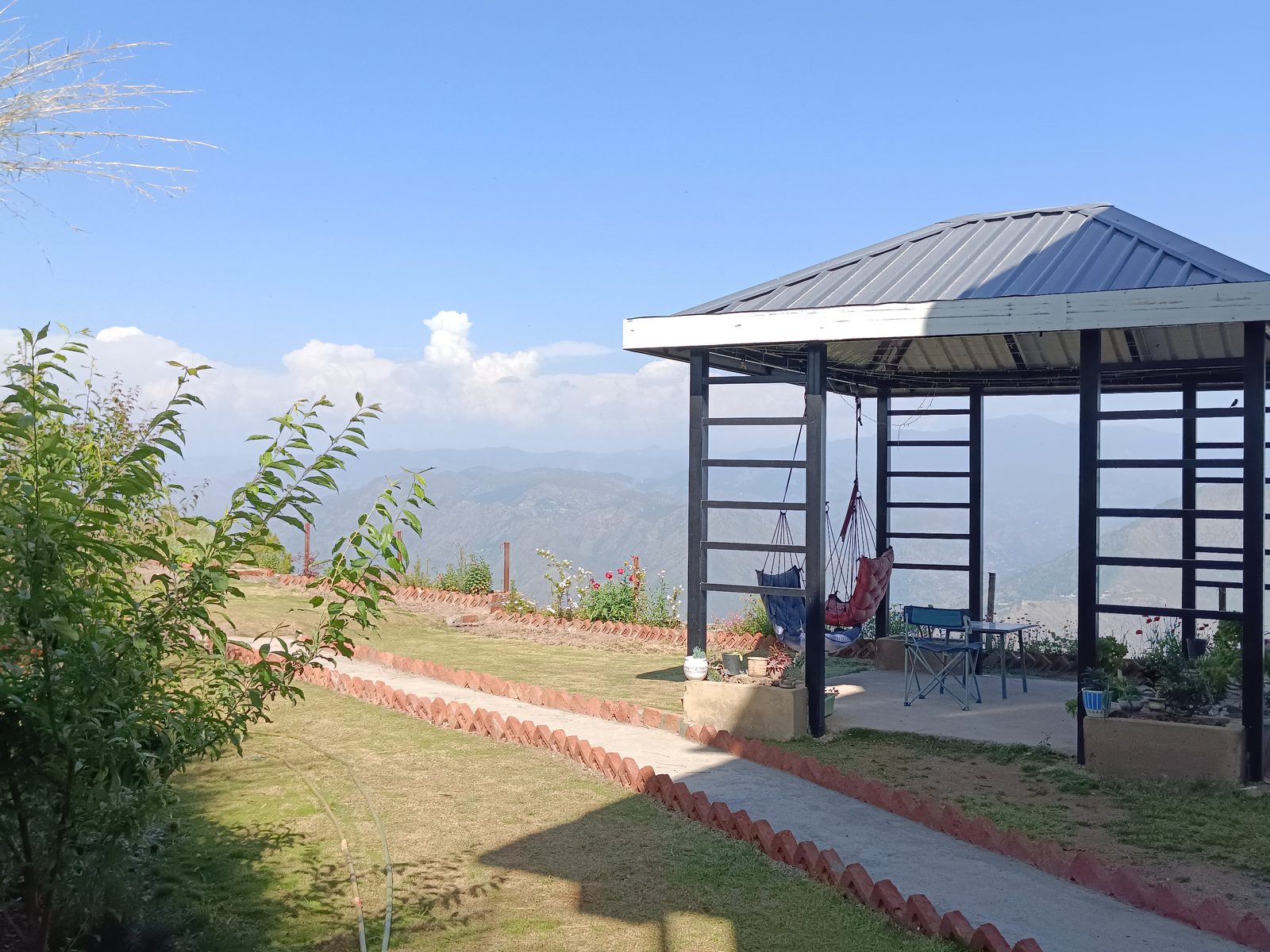 Gazebo with hanging seats and mountain range in the distance at Windmill Inn — a BnB near Solan