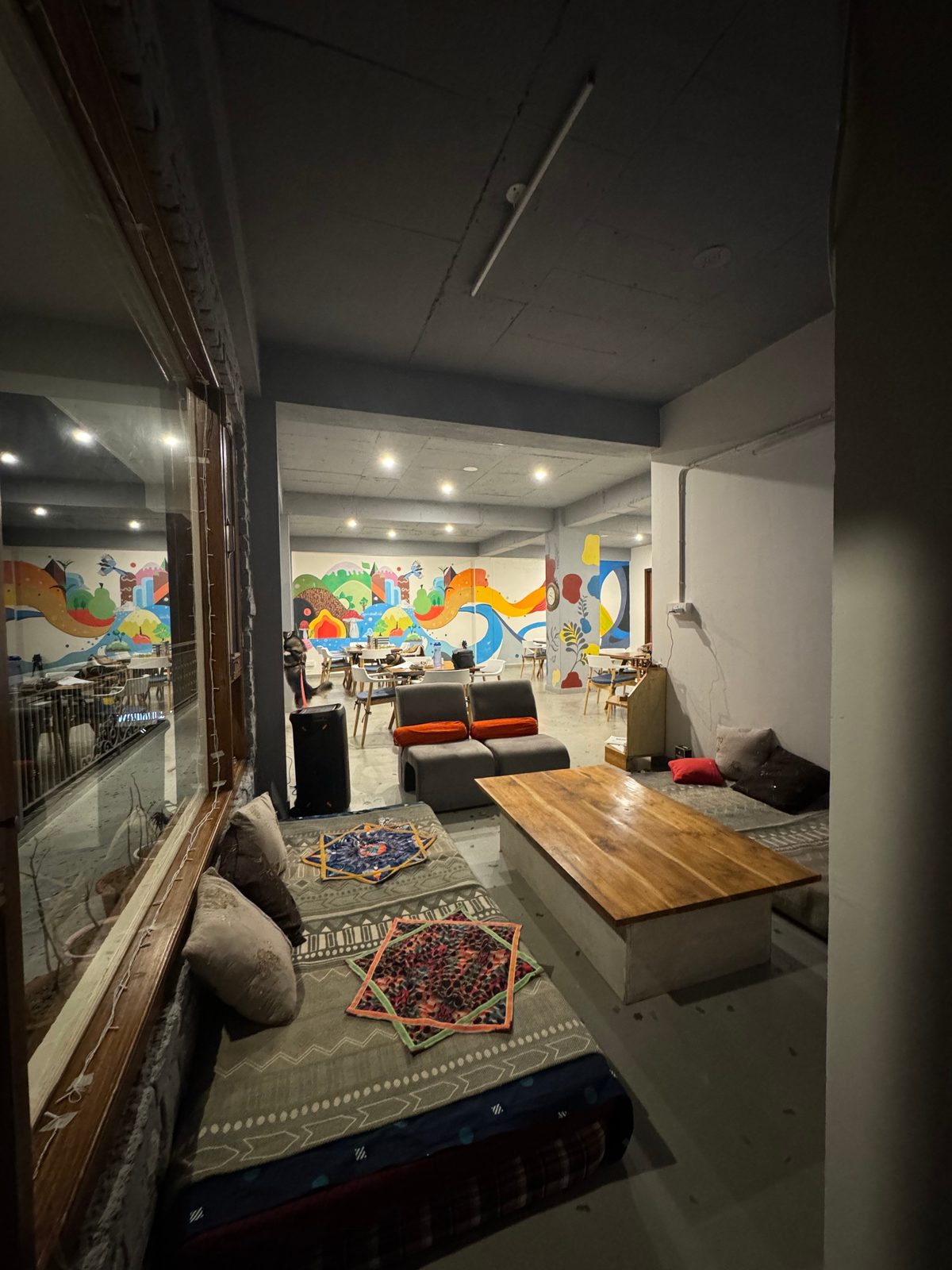Low-seating lounge corner in the café with floor cushions, rugs and a wooden coffee table