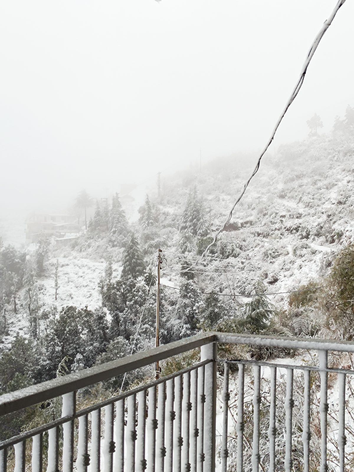 View from a Windmill Inn balcony across a snow-covered hillside and foggy valley