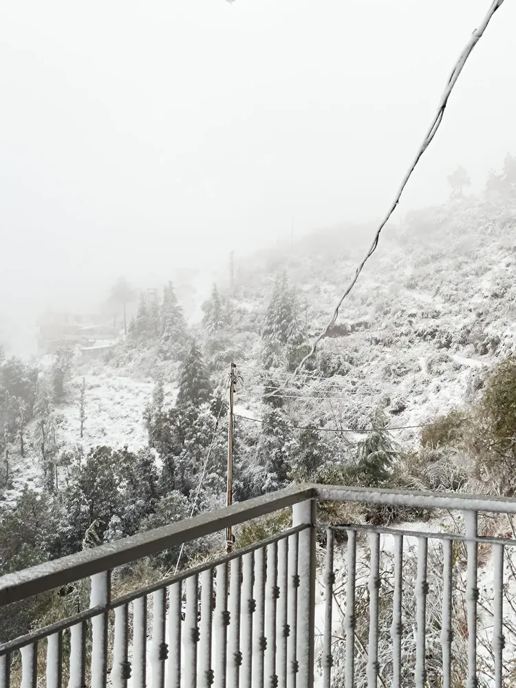 View from a Windmill Inn balcony across a snow-covered hillside and foggy valley
