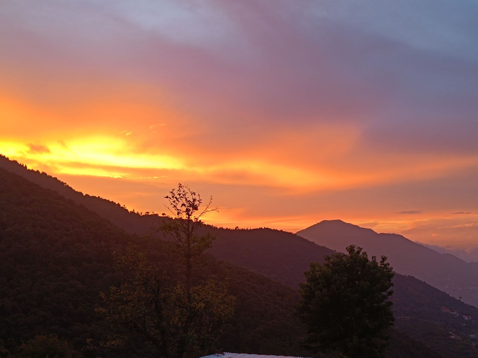 Deep red and orange sunset over silhouetted ridges — the view from the Standard room's west-facing balcony
