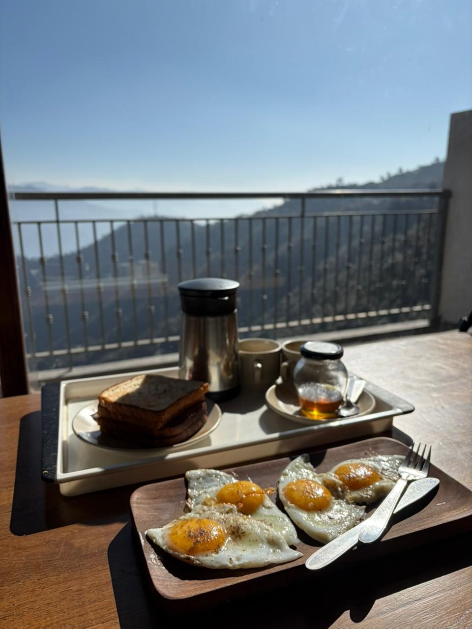 In-room breakfast on the Super Deluxe balcony — French toast, fried eggs, honey and coffee with a view of the valley