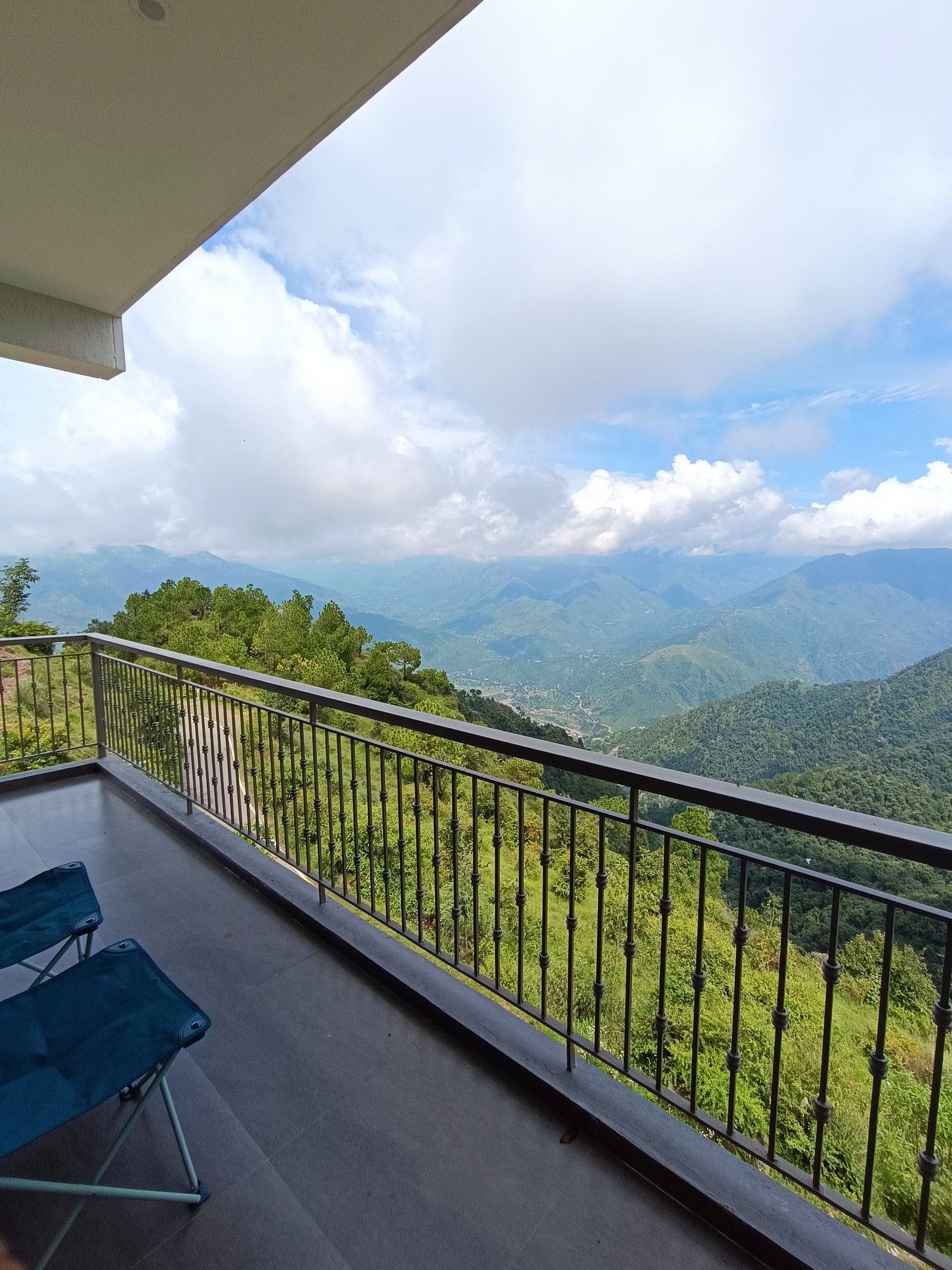 East-facing private balcony at the Super Deluxe room with chairs and a panoramic mountain view across the valley