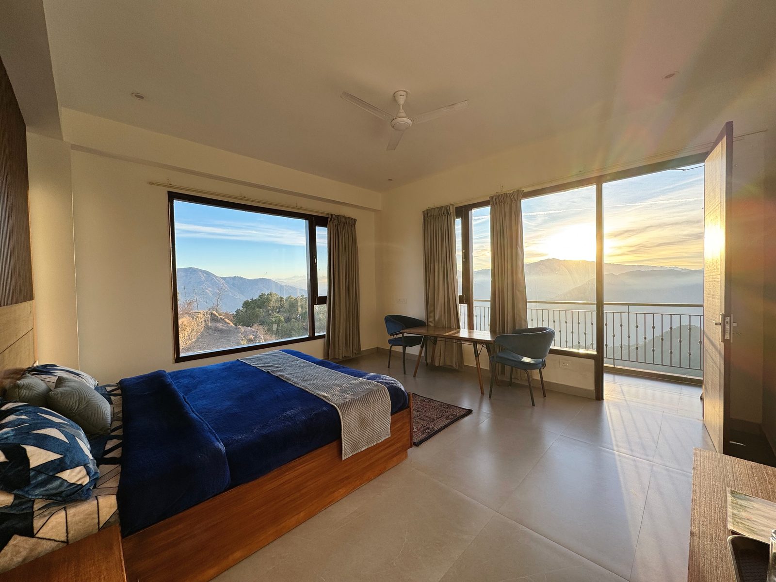 Super Deluxe room at Windmill Inn — king bed facing the mountains with sunrise streaming through the balcony doors