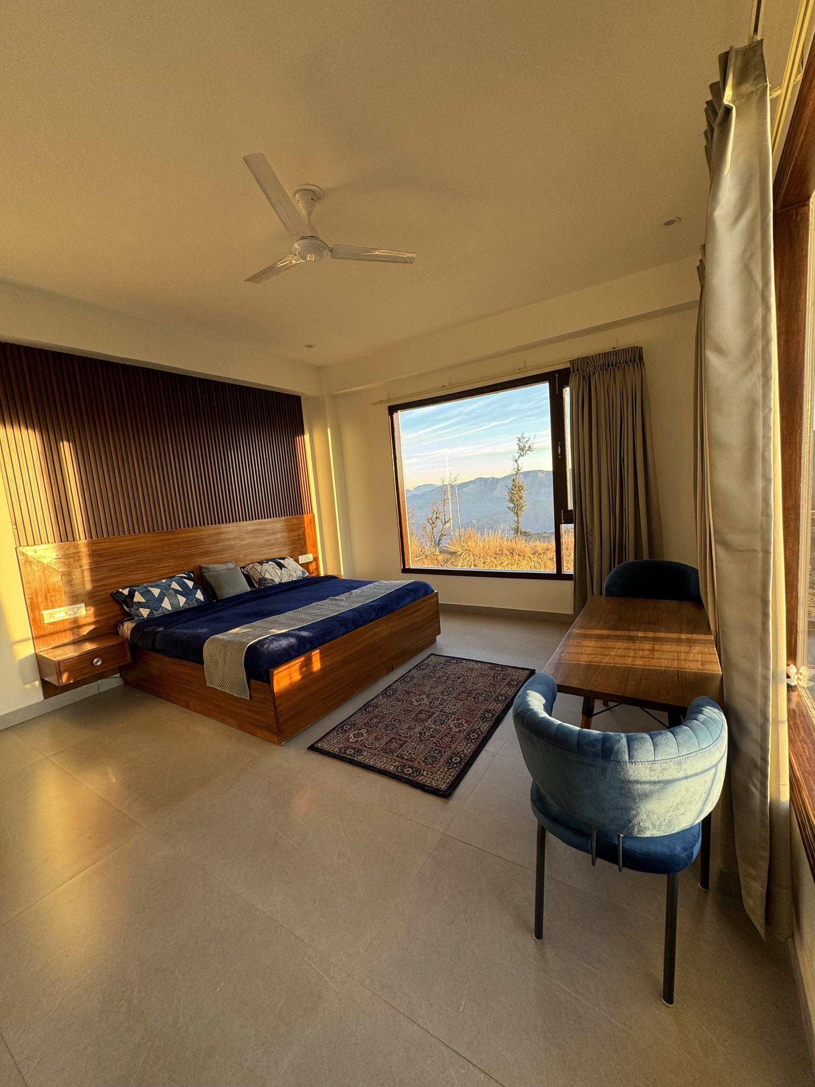 Wood-panelled headboard, work desk, rug, and side table inside the Super Deluxe room